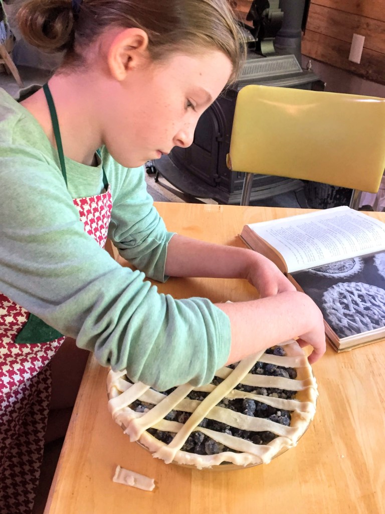 Child making blueberry pie from scratch.